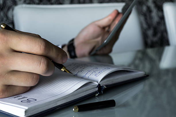 istock Close up of Man's Hand Recording in Notebook 518836627