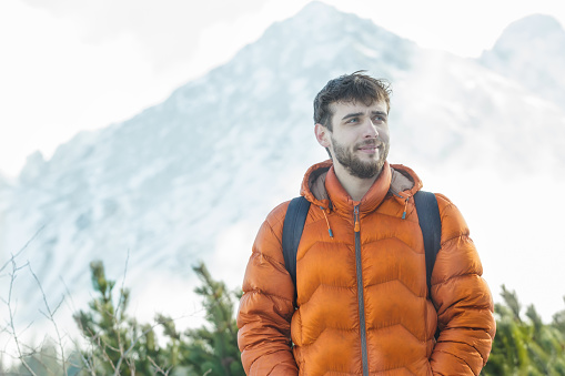 Cheerful mountaineer is standing at astonishing winter high summits landscape background