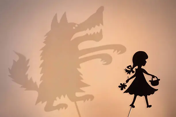 Little Red Riding Hood shadow puppet and the Big Bad Wolf's shade with the soft glowing screen of shadow theater in the background.