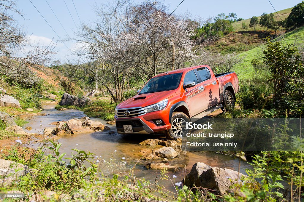 New Toyota Hilux 2015 car Hoabinh, Vietnam - Jan 10, 2016: The red New Toyota Hilux 2015 double cab 4x4 pickup truck crossing river and running on the mountain road in Vietnam. Japan-based car brand. Toyota Motor Stock Photo