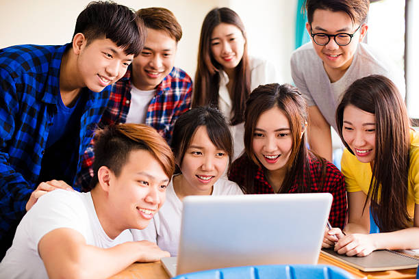Group of college students watching laptop in classroom