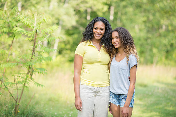 Hispanic or middle eastern Mother and Daughter posing together looking at the camera smiling