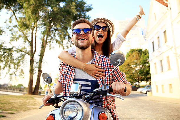 portrait de heureux jeune couple sur scooter appréciant route voyage - fille scooter photos et images de collection