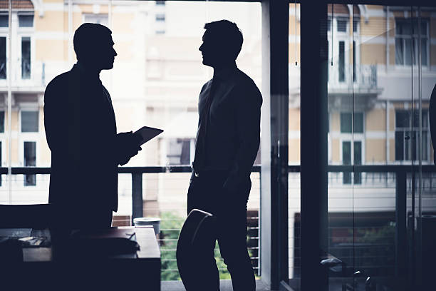 istock Silhouette businessmen discussing in dark office 518856818