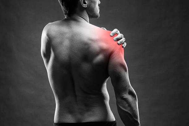 Pain in the shoulder on gray background Pain in the shoulder. Muscular male body. Handsome bodybuilder posing on gray background. Black and white photo with red dot acute angle photos stock pictures, royalty-free photos & images