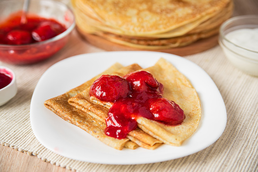 Pancakes folded triangle with strawberry sauce on a white plate