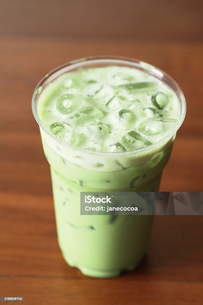 glass of milky green tea on wooden background glass of green tea latte on wooden background Brown Stock Photo