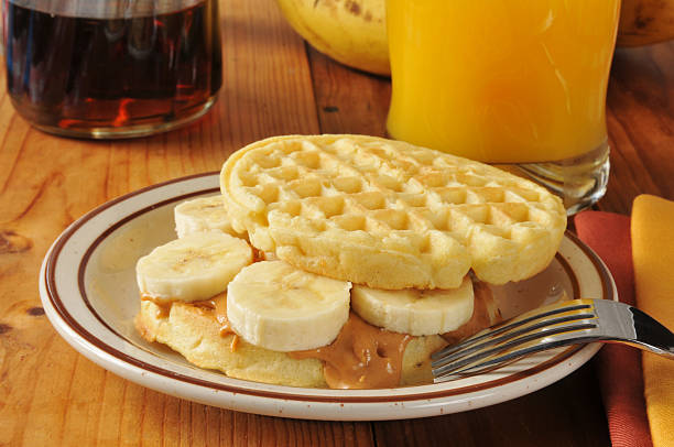 A peanut butter and banana sandwich on a waffle with orange juice