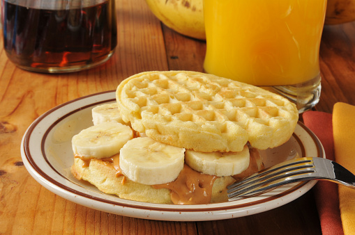 A peanut butter and banana sandwich on a waffle with orange juice