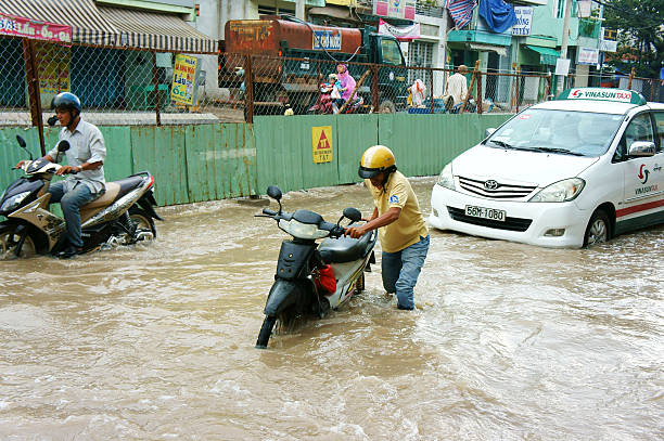 Ho Chi Minh city, Viet Nam - October 2, 2014: Group of Vietnamese people ride motorbike, bike moving on flooded street after rain, cause construction work, vehicle have to trafiic in difficult, Vietnam, Oct 2, 2014