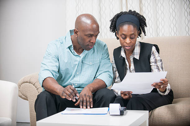 Husband and Wife Going Over Their Personal Finances A husband and wife are sitting in their home and are working on their budget and personal finances. shaved black women stock pictures, royalty-free photos & images