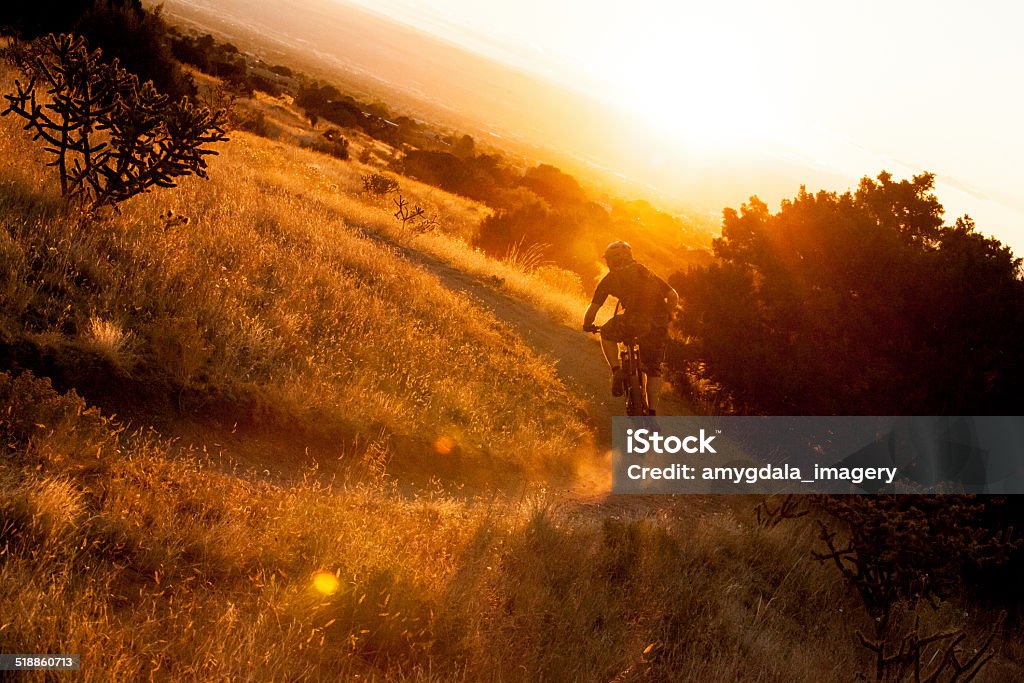 adventure golden sunshine mountain biking man at sunset catches the golden orange, red and yellow hues of sunshine.  horizontal composition taken in the sandia mountains of albuquerque, new mexico. Albuquerque - New Mexico Stock Photo