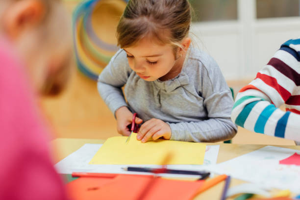 istock Happy Little Girl using scissors in kindergarten. 518868590