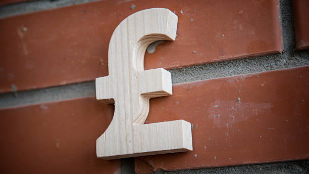 istock Wooden pound sterling symbol on a brick wall 518869882