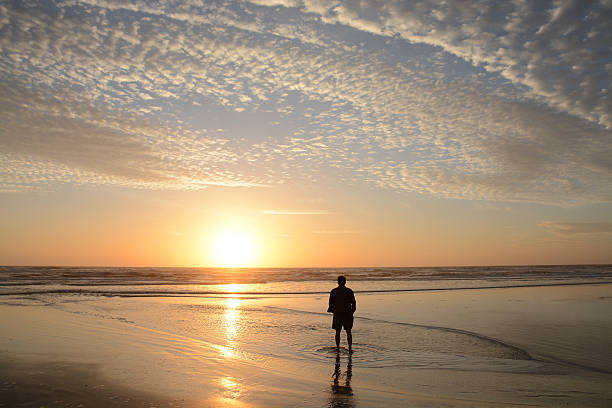 istock Man walking on the beach at sunrise. 518870104