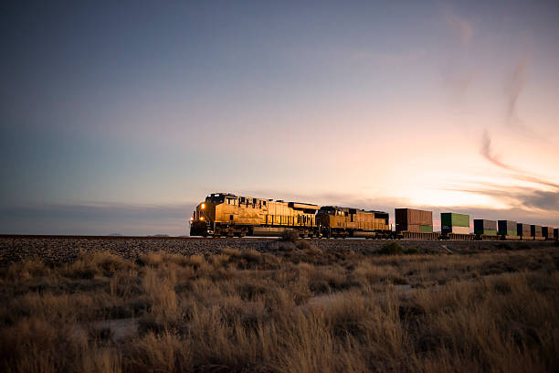 Railroad locomotive at dusk Cargo train travelling through desert. tramway stock pictures, royalty-free photos & images