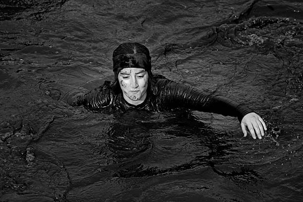 istock woman crossing canal during mud run 518872789