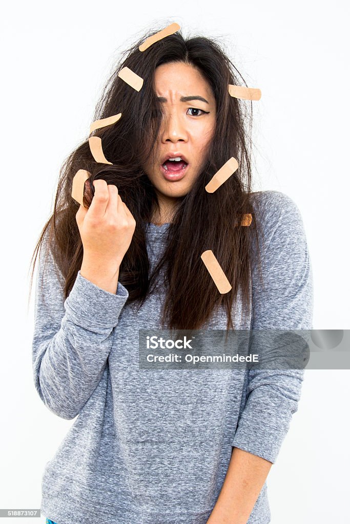 Bad Hair Day Too A beautiful young lady showing signs of fraustration over her damaged hair against a white background. Adhesive Bandage Stock Photo