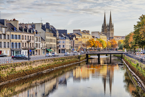 Embankment of river Odet and cathedral of Saint-Corentin reflecting in water, Quimper, Brittany, France