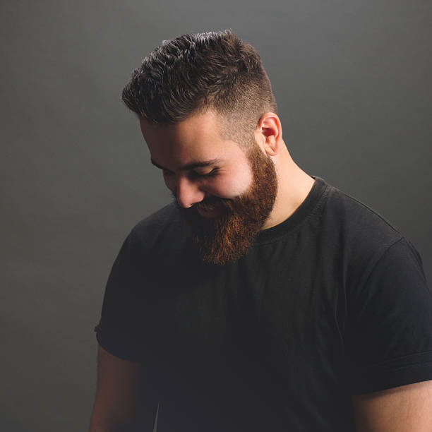 Bearded man smiling, looking down. Hipster style.