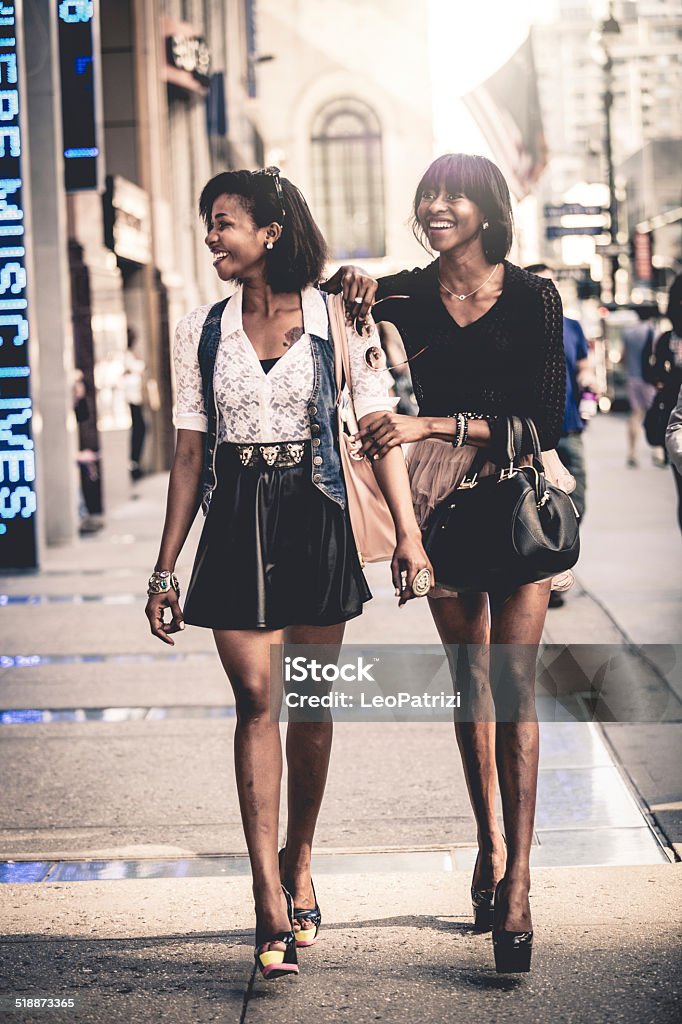 Two friends walking down the streets Two friends walking down the streets in downtown. Fashion Model Stock Photo