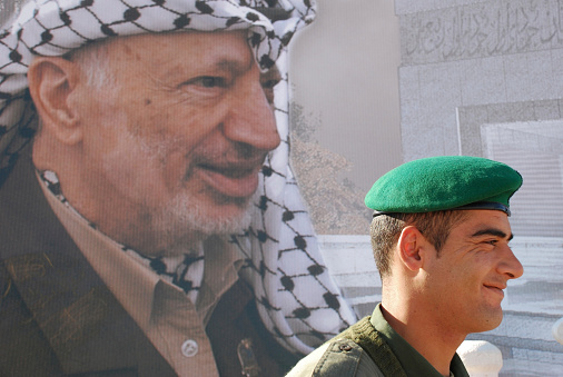 Ramallah, West Bank, Palestinian Territories - December 4, 2006: A member of the Palestinian Presidential Guard stands on duty in front of the tomb of Yasser Arafat, here still under construction with a large banner of Arafat covering the construction site. Arafat died in November 2004.