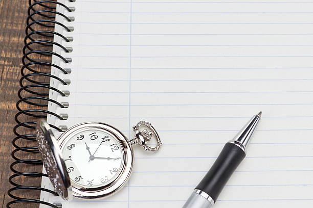 istock Pocket watch ballpoint pen on notebook for notes close-up. 518875563