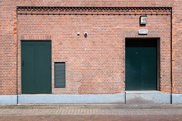 istock Old brick wall with green doors and street 518878091