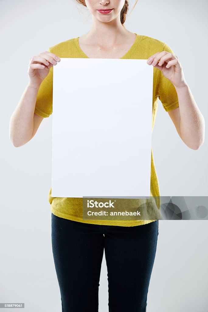 Giving you some space Cropped studio shot of a young woman holding up a white placard with copyspace Poster Stock Photo