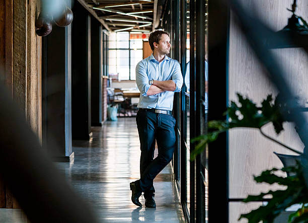 istock Thoughtful businessman standing arms crossed in office 518882484