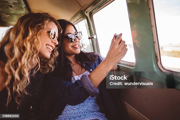 Two Hipster Girls Sitting Together Taking A Road Trip Photo Stock Photo - Download Image Now