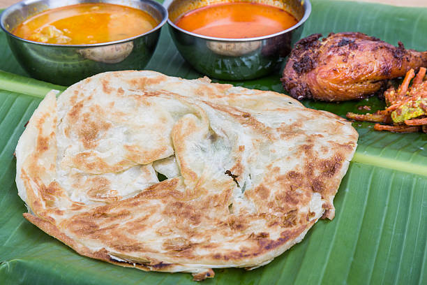 istock Traditional roti prata served on banana leaf with curry dhal. 518885304
