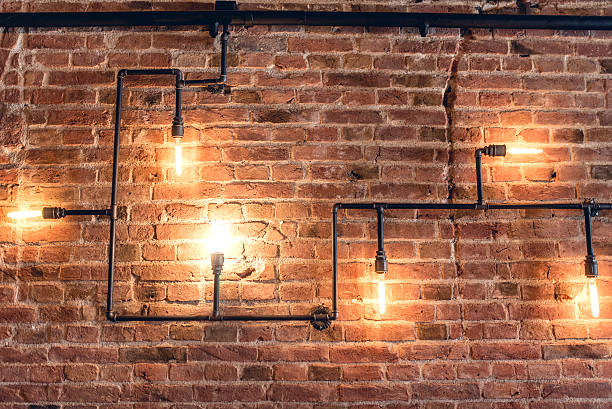Rustic design, brick wall with light bulbs and pipes interior design of vintage wall. Rustic design, brick wall with light bulbs and pipes, low lit bar interior steampunk fashion stock pictures, royalty-free photos & images