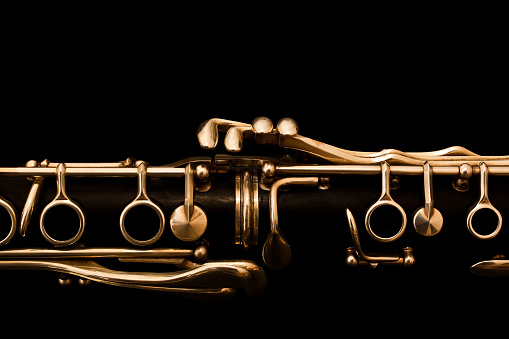 Detail of clarinet closeup in golden colors on a black background
