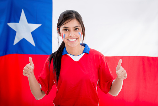 Female football fan supporting Chile with thumbs up