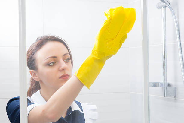 istock Young woman sponging down a shower cubicle 518897890