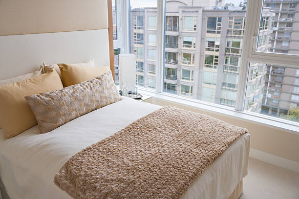 istock Soft bed beside large windows in bedroom 518898020