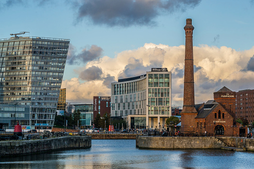 Liverpool, United Kingdom - August 22, 2014: Beautifully lit picture of The Pumphouse Pub as main focus with Hilton Hotel at the background. The Pumphouse is the Albert Dock’s former pumphouse, was built in 1870, and lovingly restored as a cosy traditional british pub, serving tasty British food.