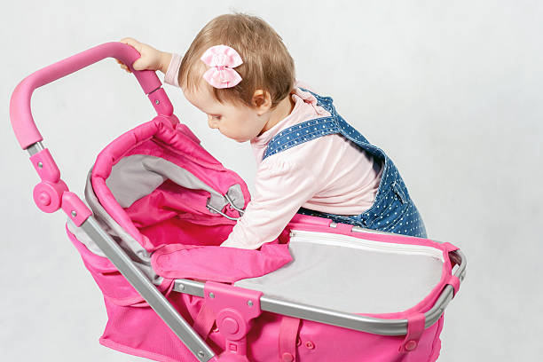 istock Cute little girl playing with baby stroller 518900340