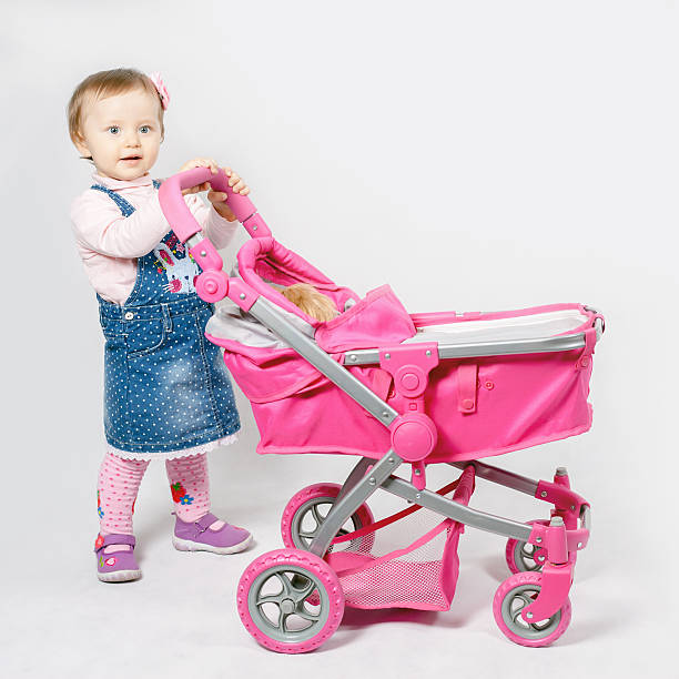 istock Cute little girl playing with baby stroller 518900492