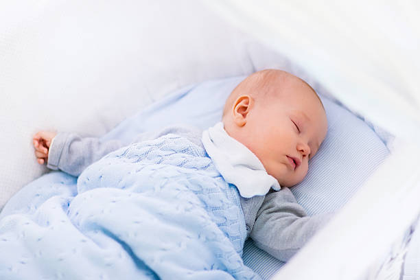 istock Baby boy in a crib under knitted blanket 518901388