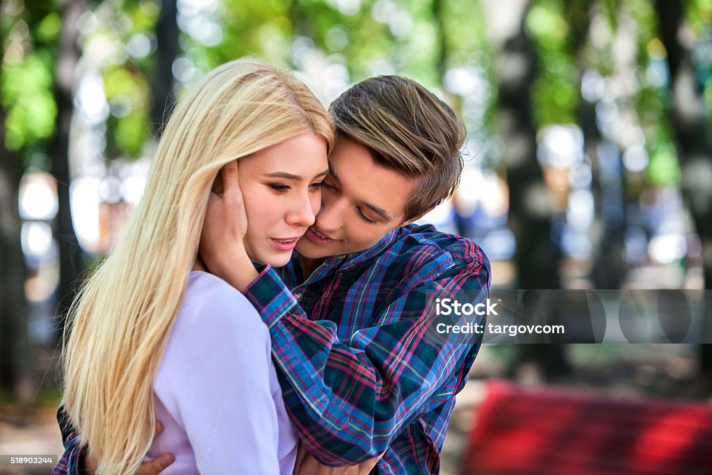 Young couple hugging and flirting in  park Young couple gently hugging and flirting in park . Activity Stock Photo