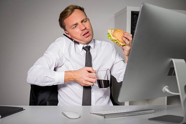 ocupado homem no escritório com café e hambúrguer - eating sandwich emotional stress food imagens e fotografias de stock