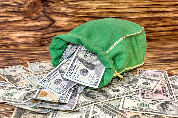 istock Bag with dollars on wooden background 518905250