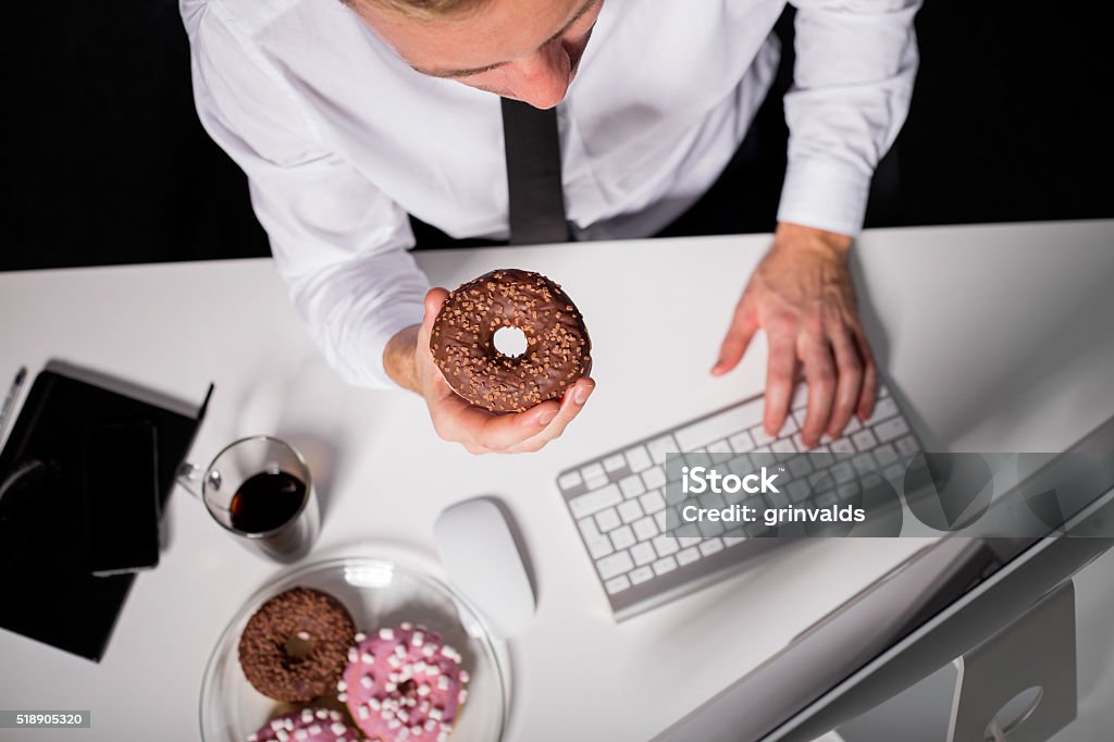 Man at the office eating donuts Office Stock Photo