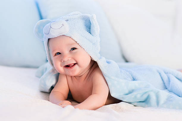 istock Baby boy in blue towel on white bed 518906652