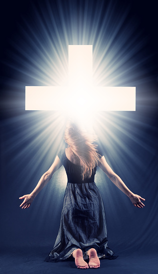 A concept image of a woman on her knees feeling the glory of Christ.