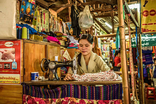 Yangon, Myanmar - January 19, 2016 : Young asian woman works at an old sewing machine at a local market in Yangon