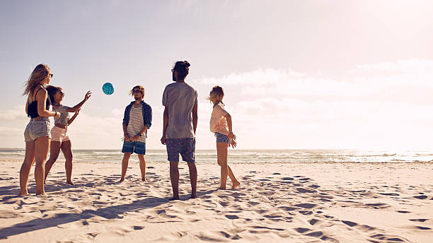 группа друзей, играя с мячом на пляже - men summer passing tossing стоковые фото и изображения