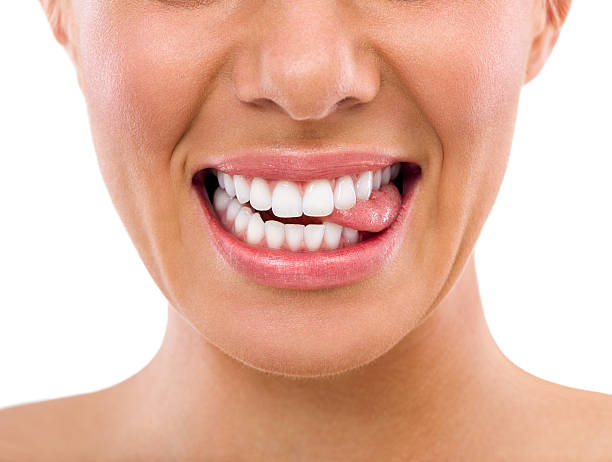 istock Female biting tongue with perfect teeth 518915089